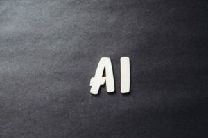 The image shows the white letters "AI" on a dark, textured background. The letters are slightly uneven and positioned closely together, creating a simple and minimalistic design. The contrast between the letters and the background enhances their visibility.